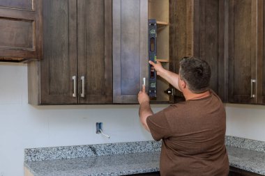 Yüklemenin yüksek kaliteli olduğundan emin olmak için yeni mutfak dolapları montajı sırasında denetmen tarafından düzey ölçüm aracı kullanılır