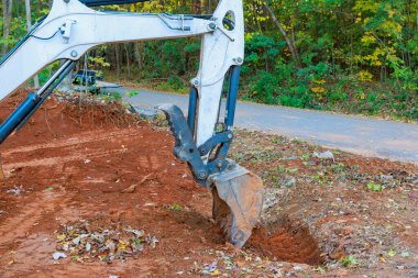 Kazıcı, yağmur suyunun yağmur suyu toplama sistemine akacağı boruları açmak için hendek kazıyor