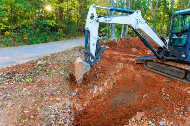 Kazıcı, toplayıcılara yağmur suyu taşımak için boru döşemek için siper kazıyor