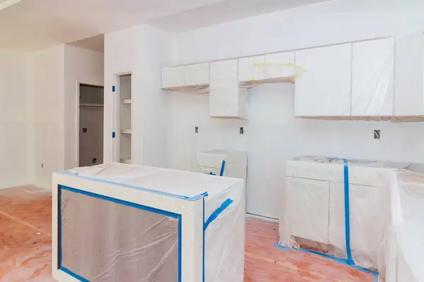 An installation white wooden kitchen cabinets is taking place in newly constructed kitchen new home