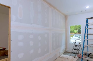 Finishing plastering drywall in ready for paint with newly constructed house construction clipart