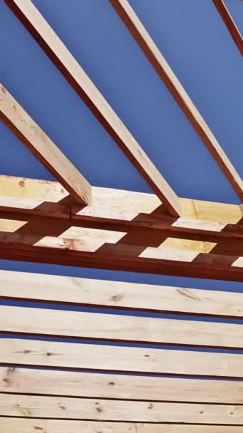木製のフレームのトラス屋根は屋根のためのサポート ビームを使用して新しい家の建築現場で造られます バーティカルビデオ — ストック動画