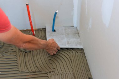 Banyo zeminine seramik fayansları yapıştırıcının üzerine yerleştiriyor.