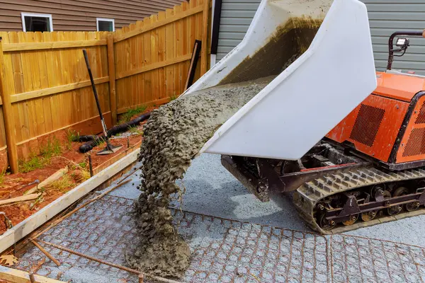 stock image Wet cement is poured into framework using self dumping track concrete buggy during construction of foundation