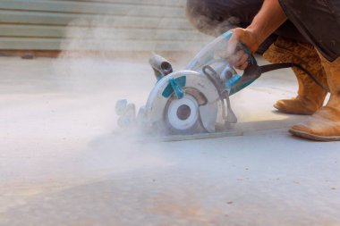 İnşaat işçisi, beton temeli döküldükten sonra kesmek için makine öğütücüsü kullanıyor