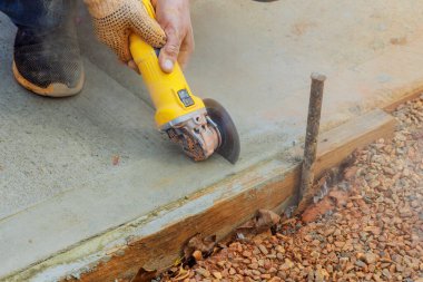 İnşaat işçisi, öğütücü kullanılarak genişletildikten sonra beton kesiyor.