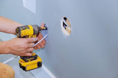 Profesyonel elektrikçi yenileme odasının elektrik sisteminin duvarına elektrik prizi yerleştiriyor.