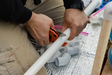 Tesisatçı plastik PVC borusunu kesmek için özel makas kullanır