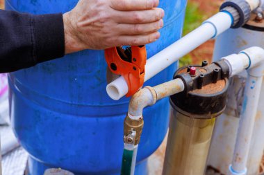 Tesisatçı, özel bir makas kullanarak plastik PVC boru kesti.