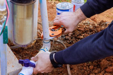 Teknisyen tamirat sırasında plastik PVC boru kesmek için özel makas kullanıyor.