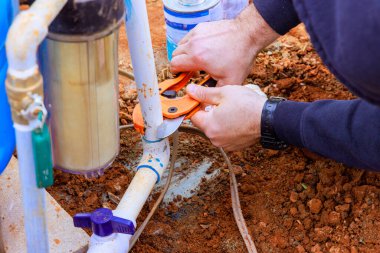 Tesisatçı özel bir makas kullanarak plastik PVC borusunu keser.