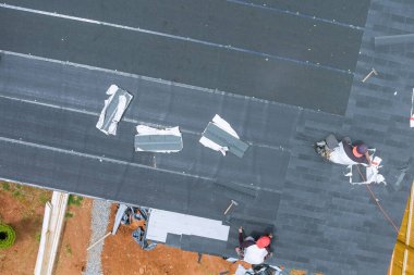 Çatıya yeni asfalt kiremitleri yerleştirmek için profesyonel çatı müteahhidi tarafından kullanılan hava çivi tabancası.