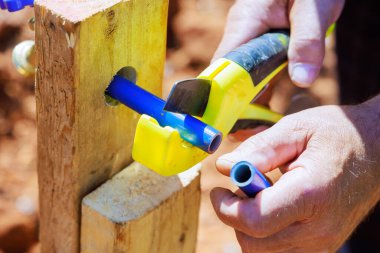 Tesisatçı testereyle mavi plastik PVC su borularını kesiyor.