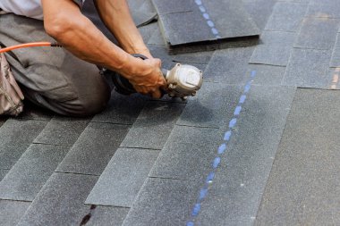 Yeni asfalt bitumen kiremitler pnömatik hava çivi tabancası kullanılarak çatı ustası tarafından monte ediliyor