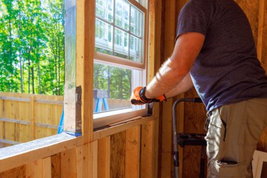 Yeni eve tornavidalı inşaat işçisi tarafından plastik pencereler yerleştiriliyor