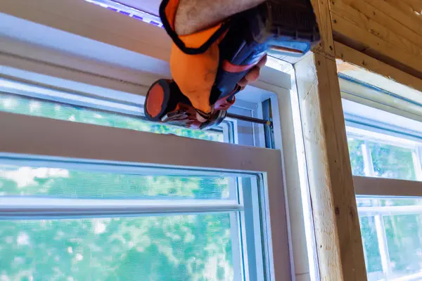 Stock image In new house, construction worker installs plastic windows using screwdriver