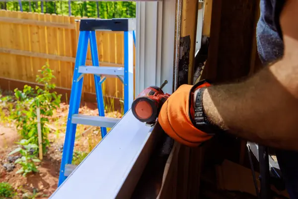 stock image New house construction worker installing plastic windows with screwdriver