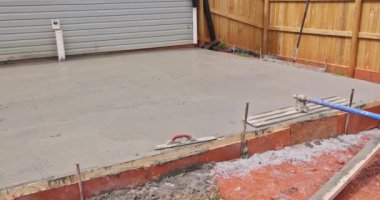 Islak beton temel havan, özel çelik mala kullanılarak inşaat işçileri tarafından dengelenir..