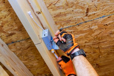 Electrician installing recessed ceiling lights with power junction box in new home