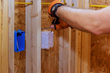 Yeni binanın inşaatı sırasında, bir elektrikçi soket kutularına kablolar bağlar