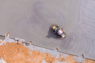 Temel beton dökülür dökülmez, işçiler beton cilalama makineleri kullanarak onu yerle bir ettiler.