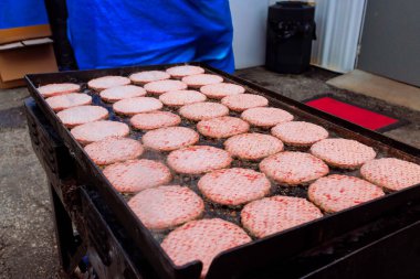 Hamburger pişirirken, aşçılar lokantadaki ızgarada burger pişirir.
