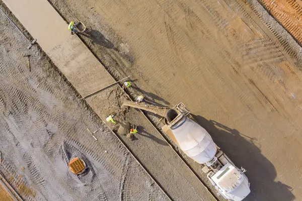 stock image Concrete is poured from mixer truck for construction of pedestrian walkway by masonry workers