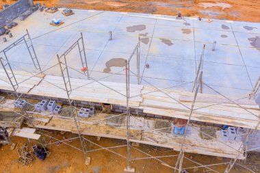 İnşaat alanındaki iskelede duran Mason, beton bloklar döşeyerek beton duvar yapıyor.