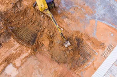 Bir kazıcı, toprak işlerinin yapıldığı yerdeki kanalizasyon boruları için siper hazırlıyor.