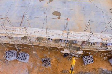 Masonluk işçisi beton bloklar kullanarak beton duvar yaparken iskelenin üzerinde duruyor.