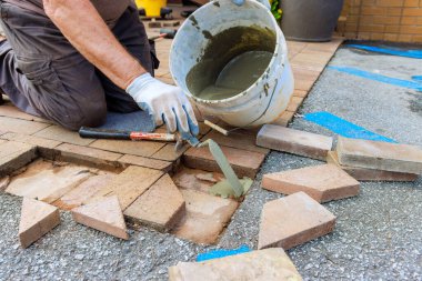 Yeniden inşa sırasında, bir çalışan hasarlı tuğlaları değiştirerek kaldırımları onarıyor