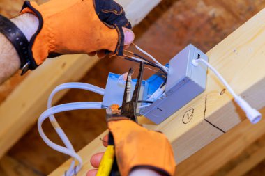 Yeni ev inşaatında, bir elektrikçi LED aralıklı tavan lambaları için elektrik bağlantı kutusu kurar