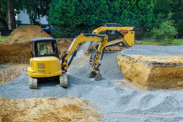 stock image When excavating irregularities on construction site, an excavator fills irregularities with granite rubble base for which concrete foundations are laid.