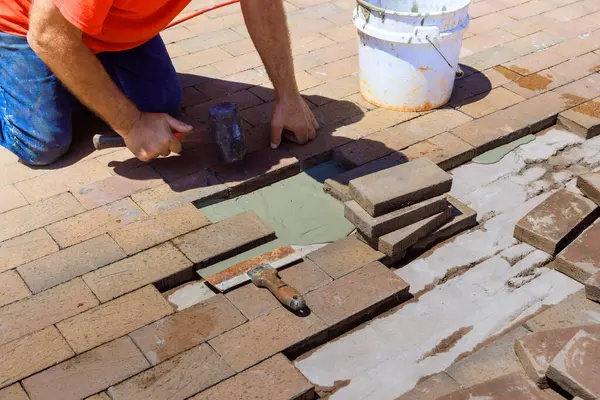 Yeniden yapılanma sürecinde, yaya yolundaki hasarlı tuğlaların değiştirilmesinden bir çalışan sorumlu.