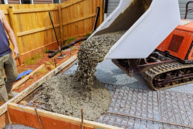 İşçiler inşaat alanlarına beton dökerken çöp arabası izi sürerler.