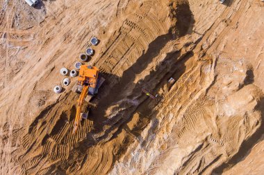 İnşaat alanındaki toprak çalışmaları sırasında, bir kazıcı kanalizasyon boruları için siper hazırlıyor