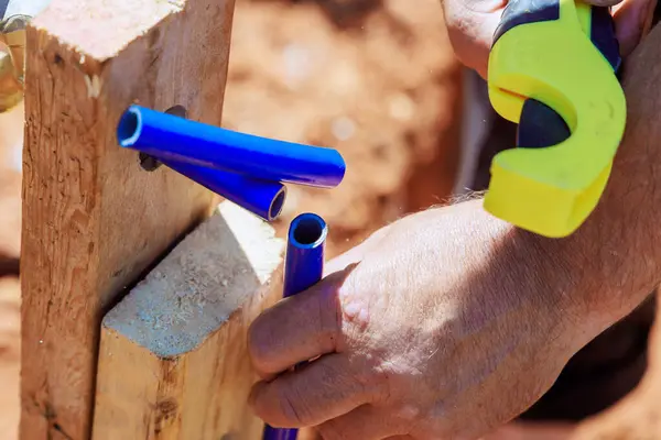 stock image Plumber using saw tools to cut plastic blue PVC water piping system