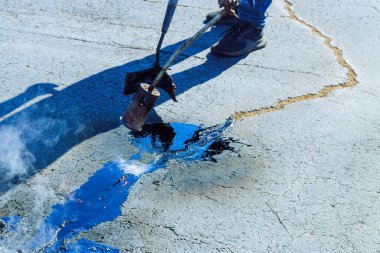 Joint seal restorers at parking lots heat cracks in asphalt before they are filled with hot bitumen emulsion clipart