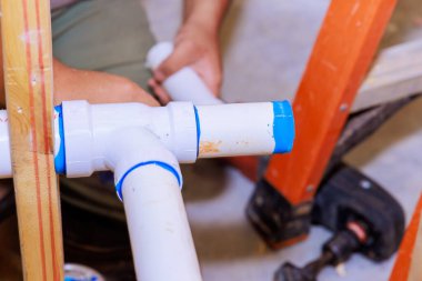 Teknisyen plastik PVC borularına yapıştırıcı sürüyor.