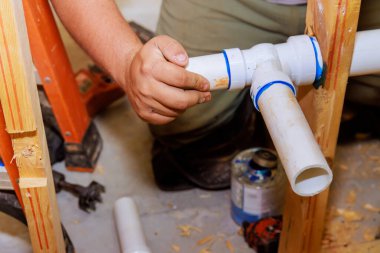 Plastik PVC borularını birleştirmek için yapıştırıcı kullanıyor.