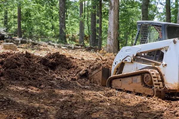 stock image An earthmoving tractor levels ground during backyard construction project