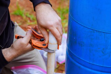 Su boruları monte edilirken, tesisatçılar PVC borusunu kesmek için özel makas kullanıyorlar.