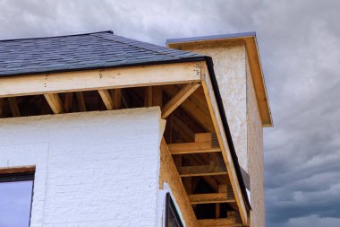 İnşaat halindeki evde, kontrplak içeren kiriş iskeleti monte edilir, soffit fasya için oluk tutucuları kırpılır