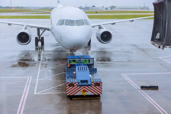 stock image During rain, preparation for departure airplane is rolled out from terminal gate ready for takeoff