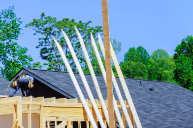 İşçi, yeni inşaat sırasında tahta çerçeveleri çivilerken hava çekici kullanarak kirişler kuruyor