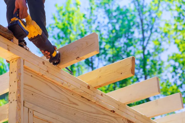 stock image Contractor builder uses cordless reciprocating saw to cut beam during construction