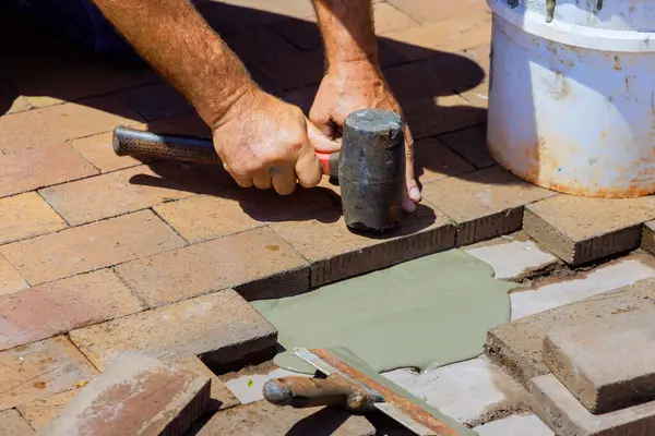 stock image As part of reconstruction process, an employee is replacing damaged bricks on footpath