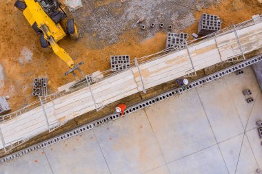 İskelenin üzerinde duran tuğla ustası beton bloklardan beton duvarlar inşa ediyor.