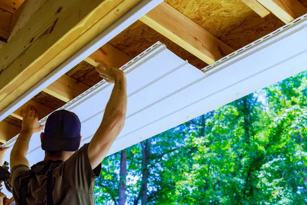 stock image Having new employee install vinyl soffit plastic panels on facade ceiling of new house