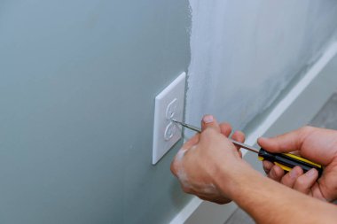 Ev yeniden inşa edilirken, elektrikçi bir prizin yerini alıyor.